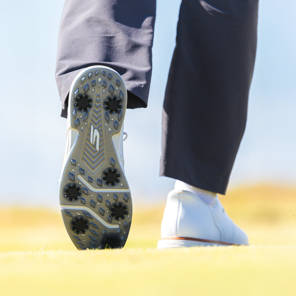 The bottom side of a persons left golf shoe showing the black widow spikes attached.