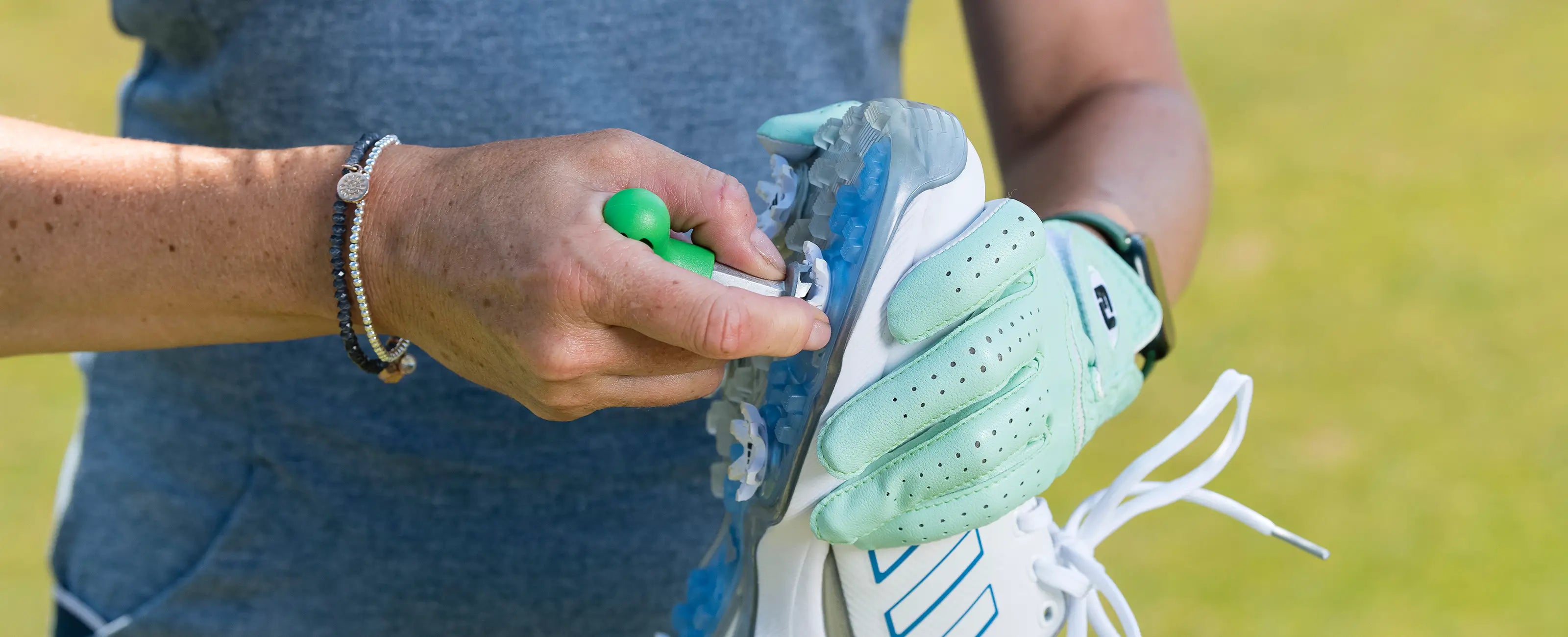 A person using a wrench to install a spike on their golf shoes.