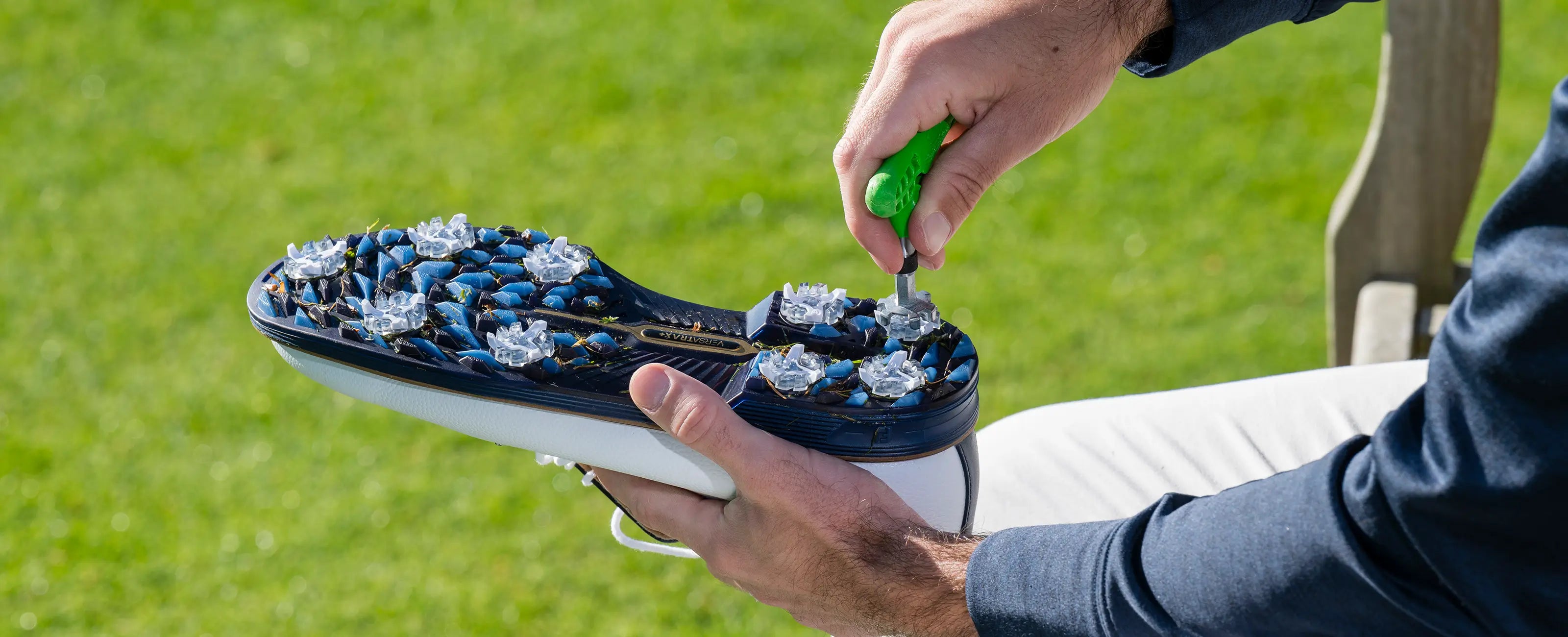 A person using a cleat wrench to install a spike on their golf shoe.