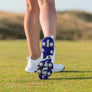 A close-up of a golfer's footwear, showcasing the sole of a white golf shoe with spikes, set on a grassy field.