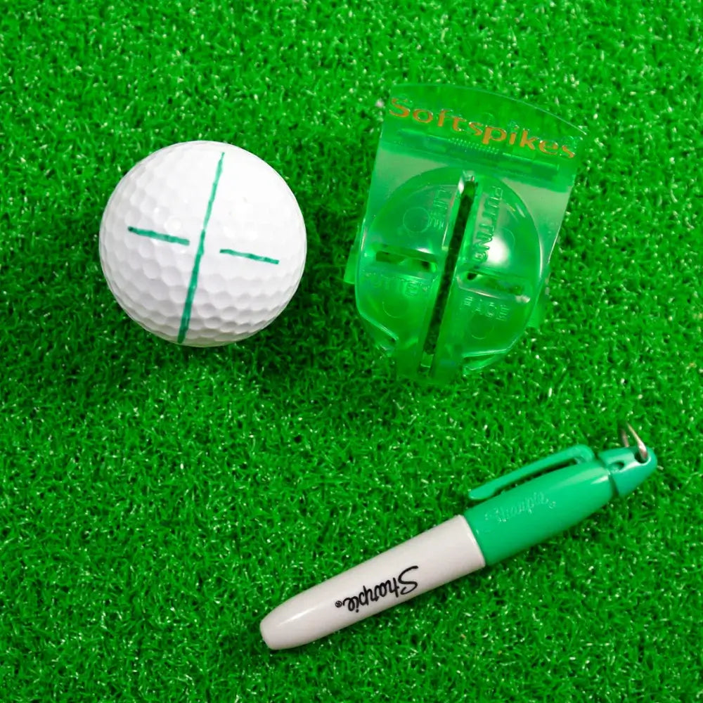 Golf ball with a sharpie and alignment tool on green grass