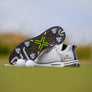A close-up of a pair of golf shoes with white tour flex pro spikes on grassy terrain.