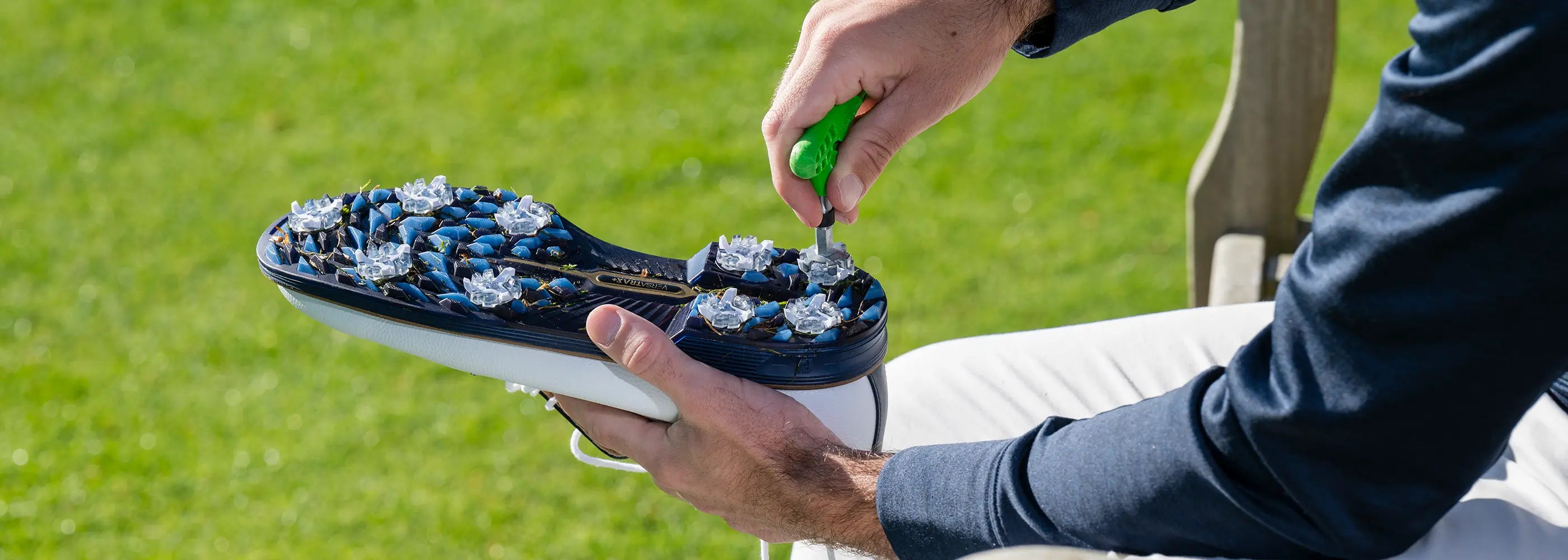 A person using a cleat wrench to change out the tour flex pro golf spikes on his shoe. 