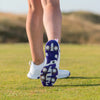 A close-up of a golfer's footwear, showcasing the sole of a white golf shoe with spikes, set on a grassy field.